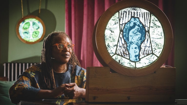 Artist Patricia Dixon in the Study at Killerton with backlit roundels of stained-glass art